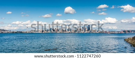 A panorama view of the Seattle skyline with puffy clouds above.