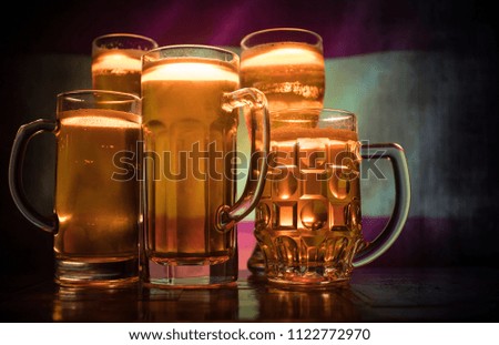 Creative concept. Beer glasses on table at dark toned foggy background with blurred view of flag of Spain. Support your country with beer concept. Selective focus