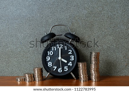 Alarm clock and step of coins stacks on working table, time for savings money concept, banking and business idea.