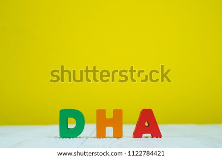 DHA text alphabet on white wooden table. yellow wall background with copy space for add text.