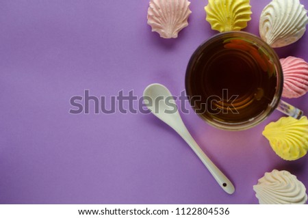 Yellow pink and white marshmallows and tea on pastel purple  background 