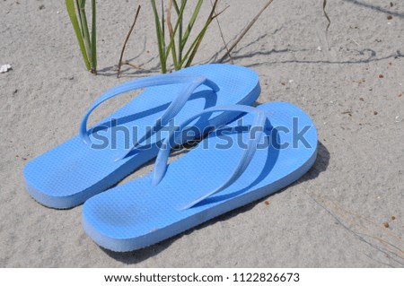 blue flip flops sitting on the sandy beach