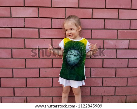 The child plays football, kicks the ball, scores a goal, rejoices and is sad. Brick wall background. Close-up photo.