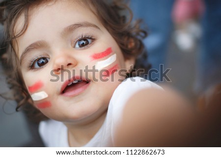 Kid fan with red and white flag painted on face