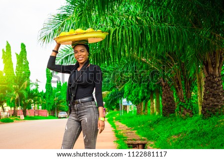 smiling girl carrying a tray of mangoes. 