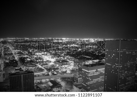 The glittering city of Houston from the penthouse level of a high rise building.