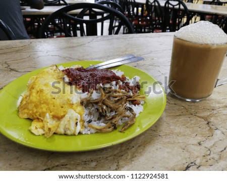 Nasi lemak, a traditional Malay curry paste rice dish serve together with fried egg and a glass of Teh Tarik.

