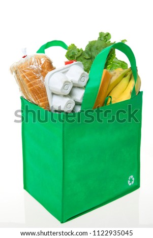 A reusable grocery bag with recycle symbol, filled with basic groceries. Royalty-Free Stock Photo #1122935045