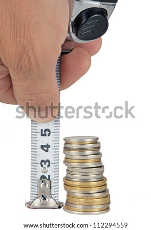 Human hand measuring a pile of coins with ruler