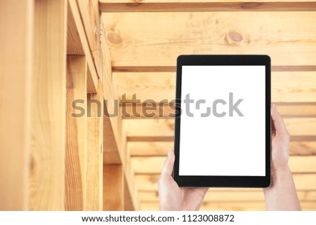 Tablet in the hands of Mrs. architect during a control visit. Construction of a wooden house, isolated blank screen with copy space.
