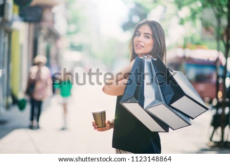 Portrait of woman holding paper bags and coffee on the street after shoping. Royalty-Free Stock Photo #1123148864