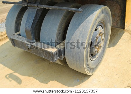 Asphalt road surface after compacting with rubber-tired road rollers.Close up rubber-tired road rollers rear wheels on asphalt road.