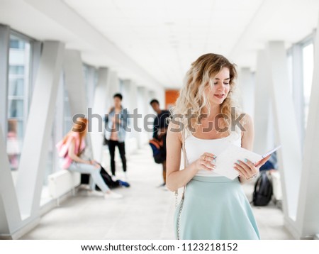 Young beautiful student standing with a notebook at the University. Students in the background. The photo illustrates education, College, school, or University.