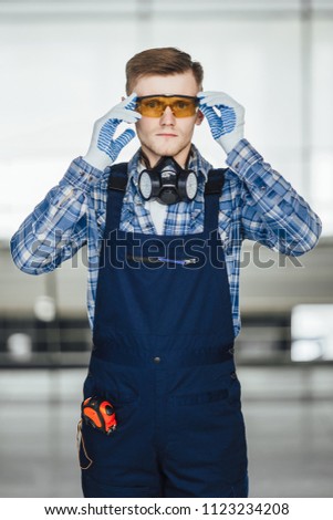 The builder in a uniform, stands and looks to the camera in a modern home