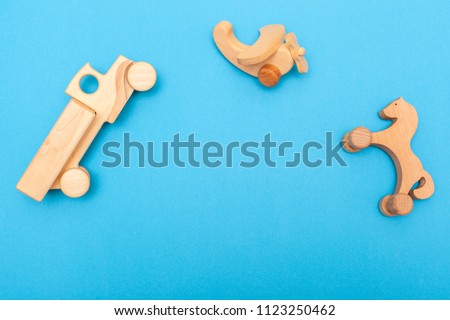 Wooden children's handmade toys: airplane, car, horse on a blue background close-up with space for text. Baby things baby, developing games for the smallest, natural and environmentally friendly toys