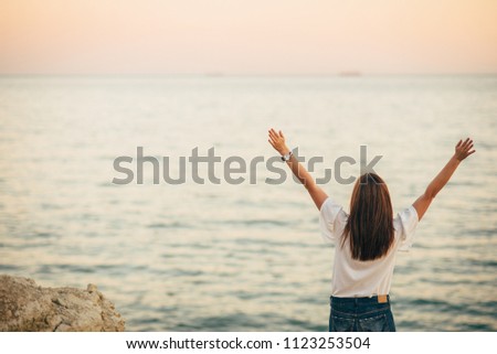 Beautiful woman sitting on a rock and looking to the sea. Soft focus.
