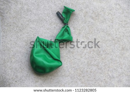 Image of a green balloon on old cream colored tile floor.
