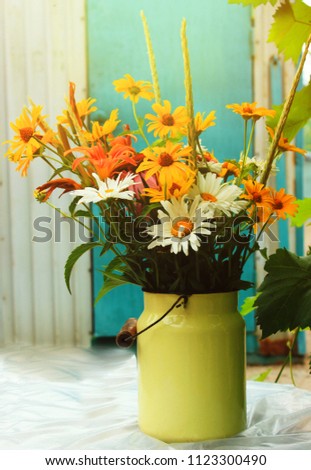 Bouquet of bright flowers on blue background in water can. Bright nature. Summer bouquet