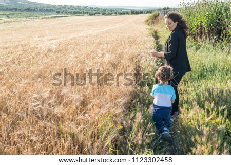 A woman an a child next to a wheal field at sunset.