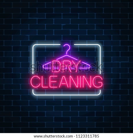 Neon dry cleaning glowing sign with hanger on a dark brick wall background. Cleaning service signboard design.