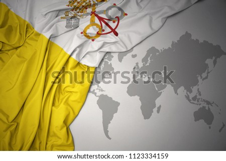 waving colorful national flag of vatican city on a gray world map background.