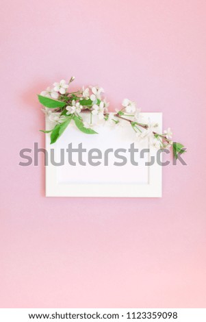 Creative flat lay concept top view of blank frame mock up and cherry tree flowers on millennial pink background with copy space in minimal style, template for lettering, text or your design