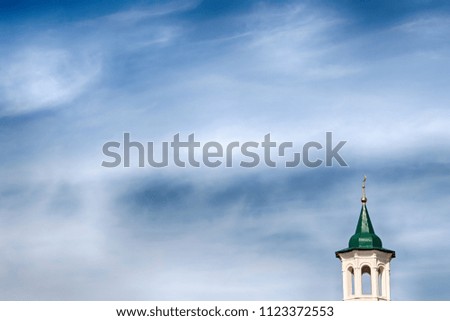 Minaret with green roof against the blue sky