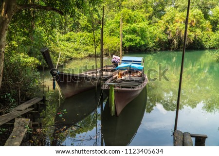 A small fishing boat is parked at puddle in a mangrove forest ecosystem with Mangrove roots at Thapom, Klong Song Nam, Krabi, Thailand. Royalty-Free Stock Photo #1123405634