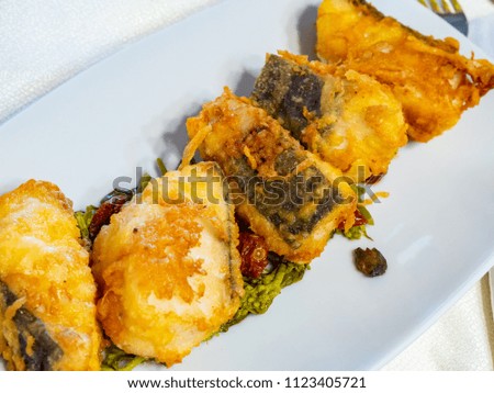 tasty pieces of crispy fried cod, appetizing, seasoned with broccoli cooked in a pan and dried tomatoes.