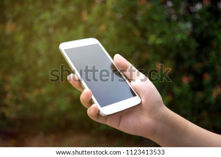 Hands holding smart phone outdoor, black screen.