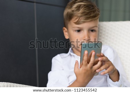 Close up of little boy using mobile phone while playing games.