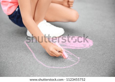 Little child drawing heart with chalk on asphalt, closeup