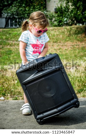Freedom music and party concept, Cute toddler girl with portable big acoustic system on urban city background