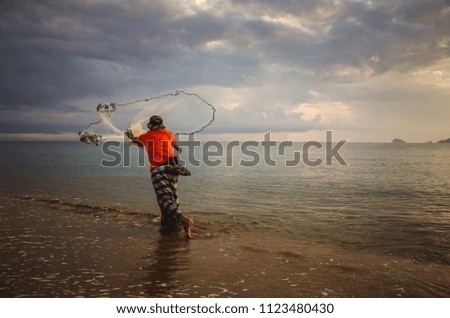 A picture of fisherman spreading his net fish to catch some fish at the beach