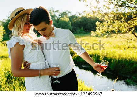 love, dating, people and holidays concept - happy couple drinking champagne on picnic over sunset background
