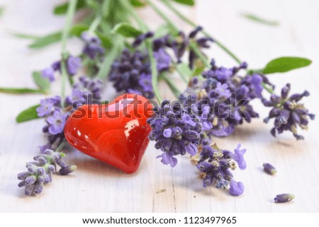 blooming lavender and a red heard from glass on a white painted wooden background, selected focus, narrow depth of field