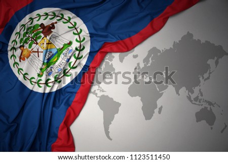 waving colorful national flag of belize on a gray world map background.