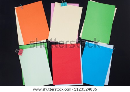 Many different colored papers for notes on a black background. Office concept. Copy space.