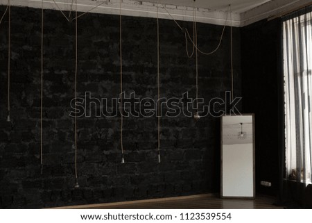 the interior of the room with a black wall. large empty room and a lamp by the window. large window in the room. large mirror by the wall