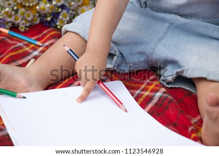 Baby sitting on a plaid and keep the pencil.