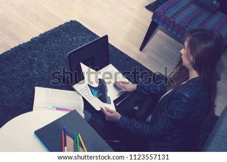 Young creative woman working on new fashion design and using laptop while sitting on the floor. 