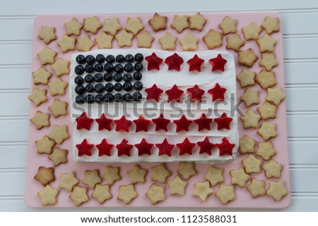 Happy 4th of July conceptual image with homemade cake that looks like American flag with many homemade star shaped cookies.  