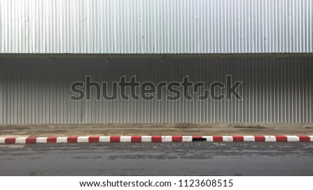 zinc sheet wall beside sidewalk. zinc sheet are protect people who walk in pavement and the sidewalk have no parking sign, red and white sign