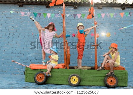 Three happy children boys and funny girl are playing on ship made from old fishing boat. Brothers and sister are happy together on vacation in village. Pirates, sea, adventures, treasures, ocean.