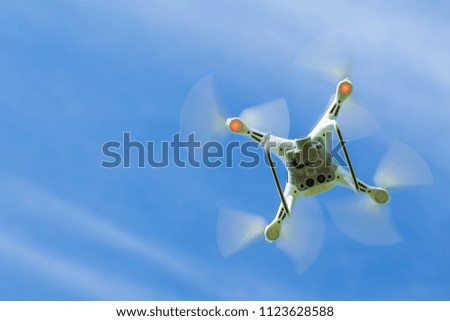 Flying drone quadcopter with digital camera on blue sky background