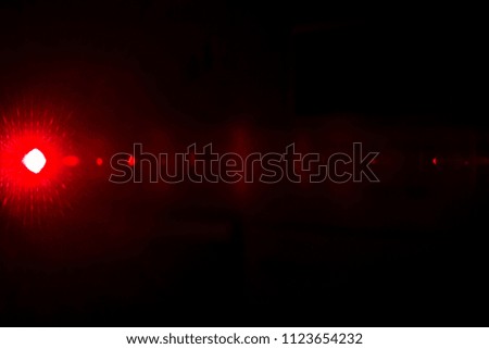 Camera lens flare by red laser light create effects depending on iris shapes, number of lens surface of objective and interference effect and moire on digital sensor on dark black background