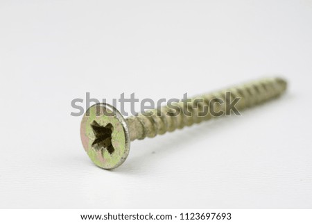 Screw head on a white table. Accessories for screw connections. Light background.