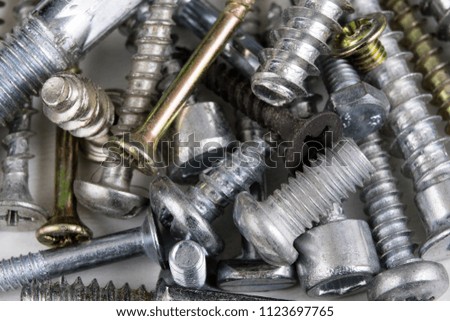 Screws on a white table. Accessories for screw connections. Light background.