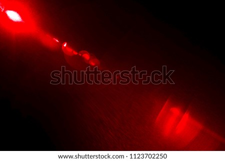 Camera lens flare by red laser light create number of circles depending on number of lens surface of objective and interference effect and moire on digital sensor on dark black background
