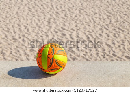ball lying on a stone parapet on a sandy beach background
